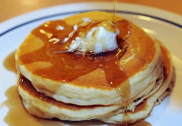 Maple syrup runs down the side of a short stack of three pancakes at the International House of Pancakes.