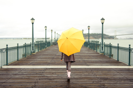 Pretty African American girl walking with umbrella on the pier in San Francisco