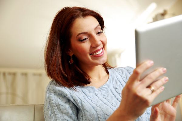 Smiling woman using tablet computer at home