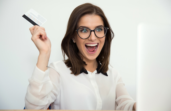 Surprised businesswoman sitting at the table with bank card