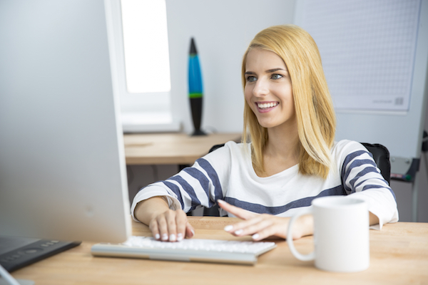 Happy female designer working on computer in office