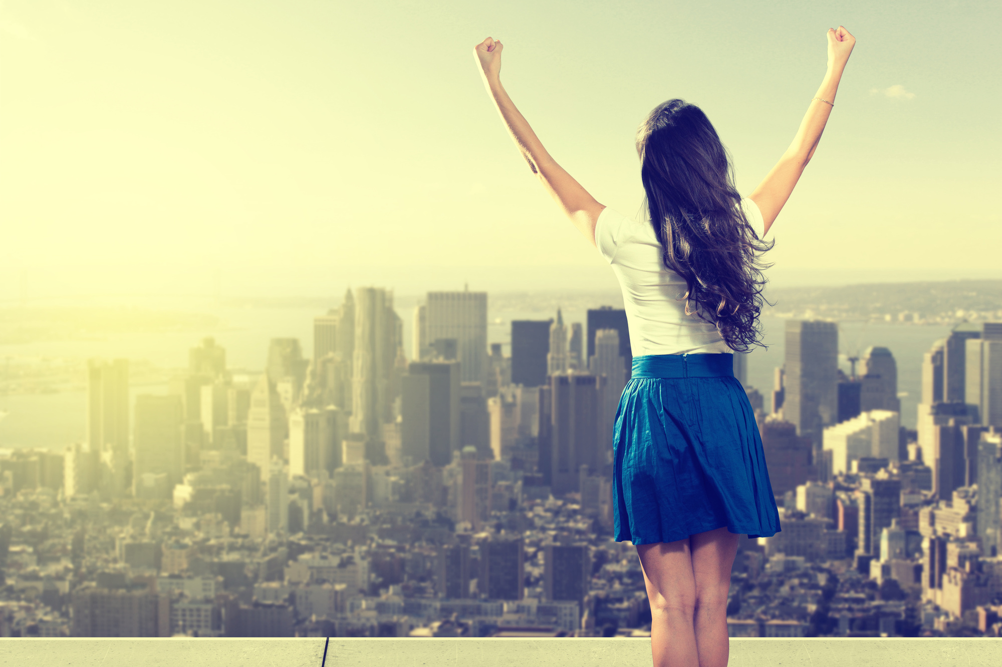 woman with arms raised looking at city