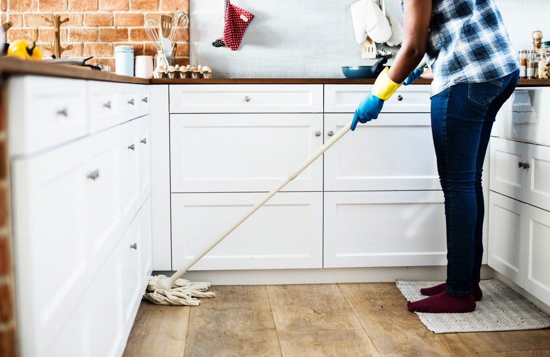 person cleaning floor with mop
