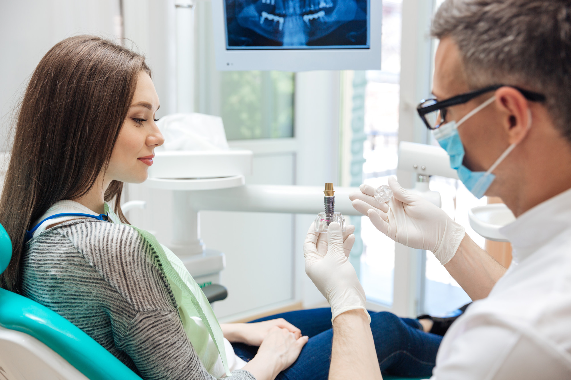 woman at dentist looking at dental implant