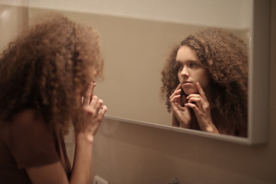 Woman Checking Skin on a Mirror